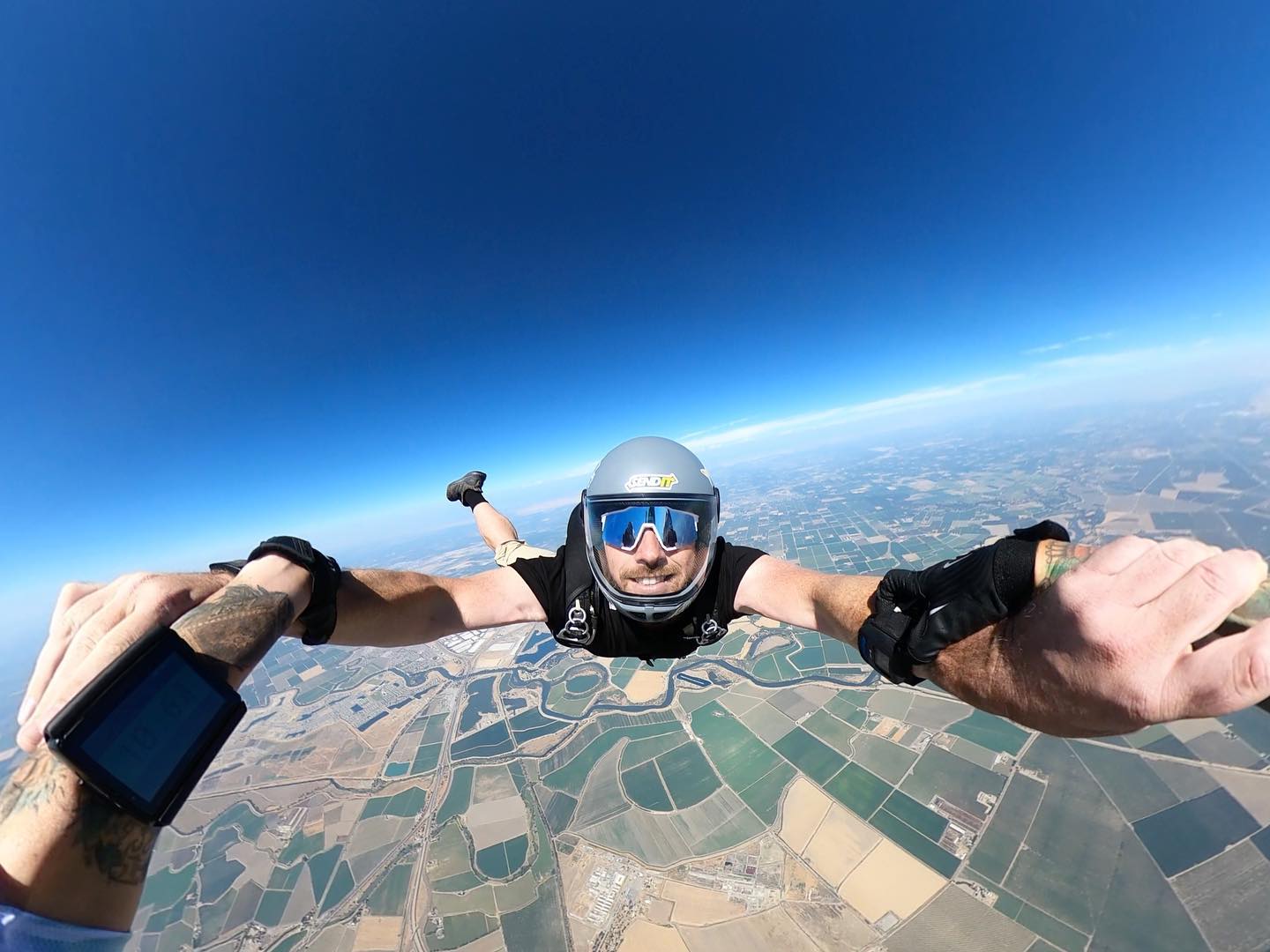 Rob Corsi skydiving above fields under a bright blue sky